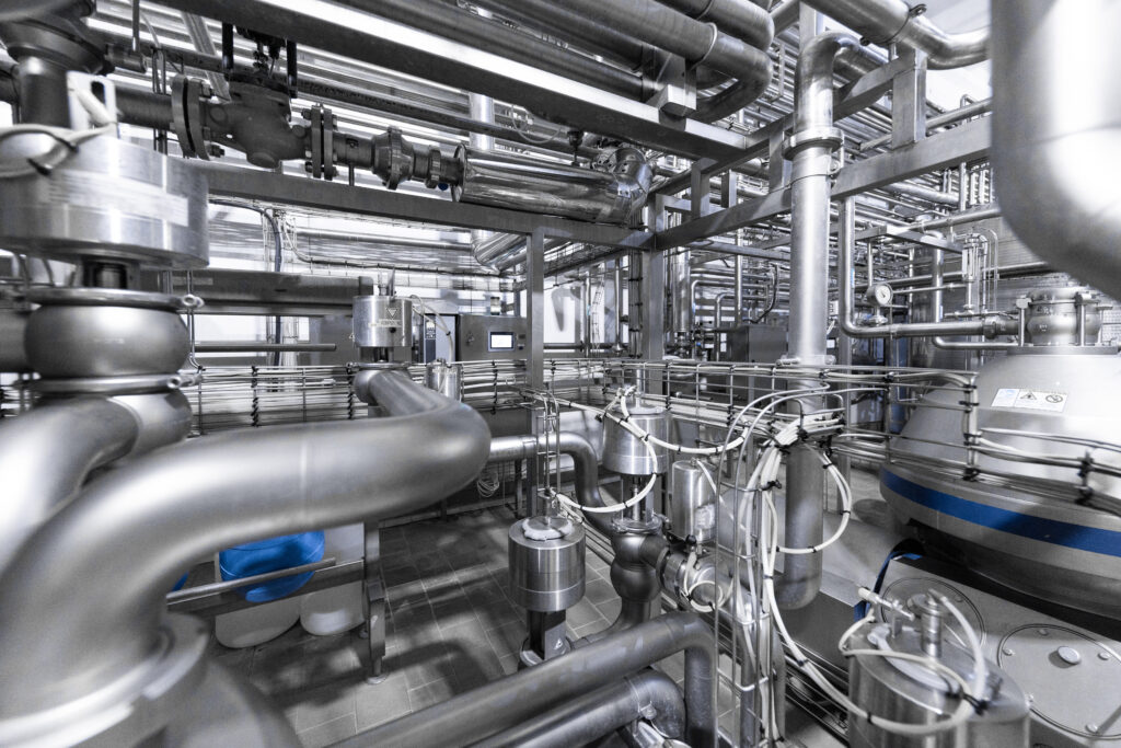 Stainless steel sanitary piping system with valves and processing equipment in industrial facility