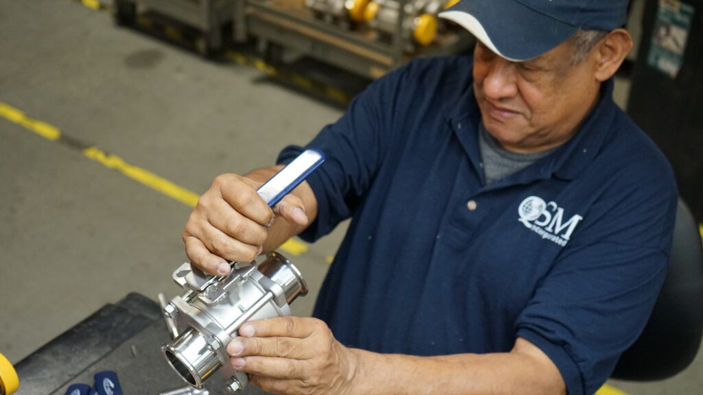 Technician adjusting stainless steel sanitary ball valve during assembly and inspection
